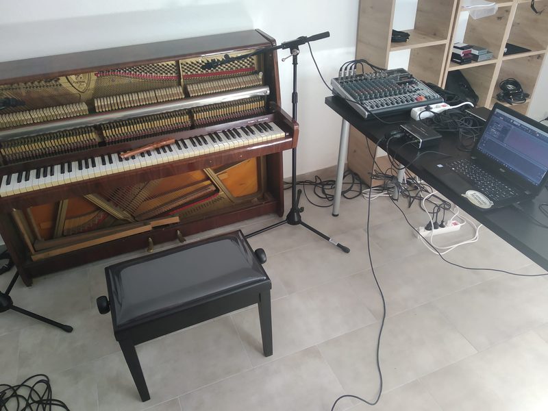 The Petrof upright in the house with a microphone, a mixer and a laptop, set up for the recording