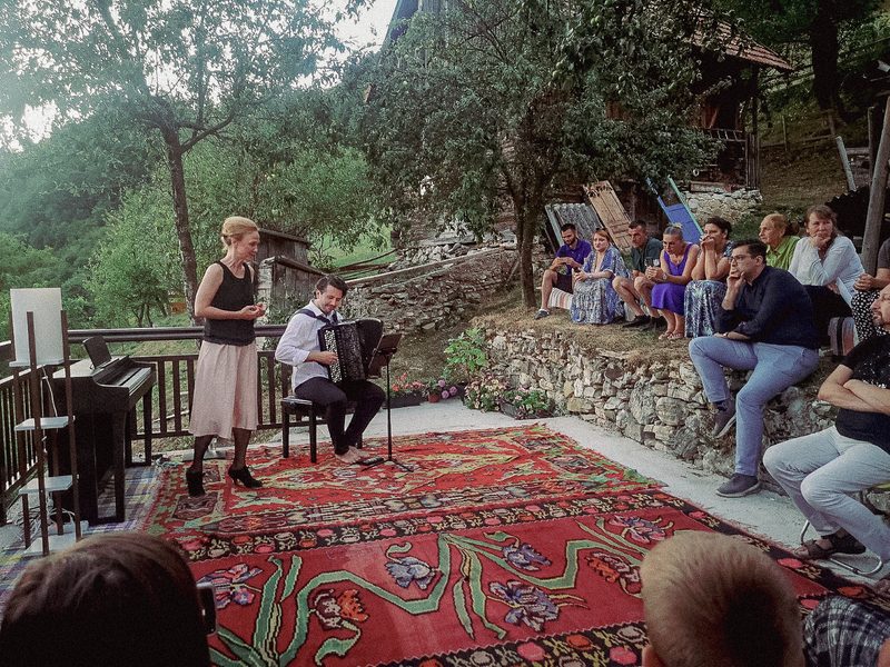 A singer on the terrace in Mijakovići, the audience seated on carpets and benches